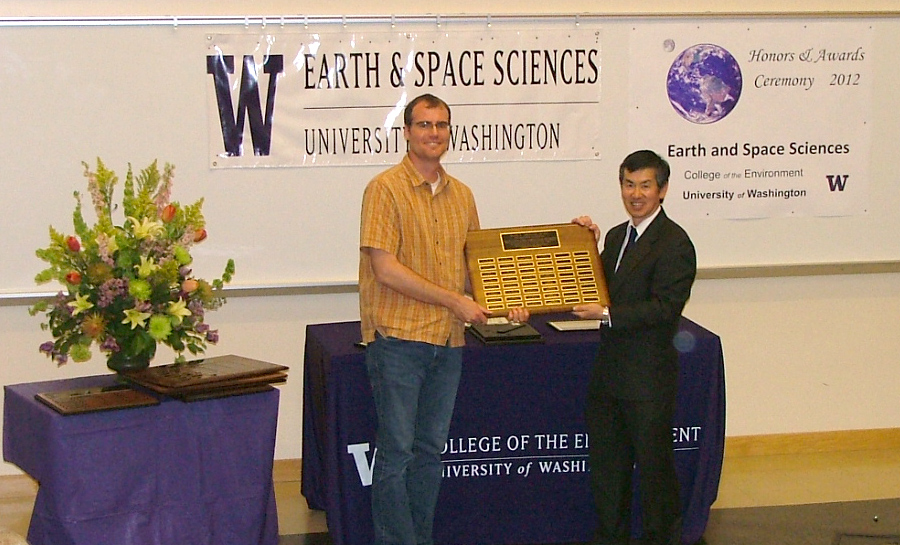 Photo of Isaac Larsen receiving the Johnston Prize for Research Excellence from Robert Winglee.